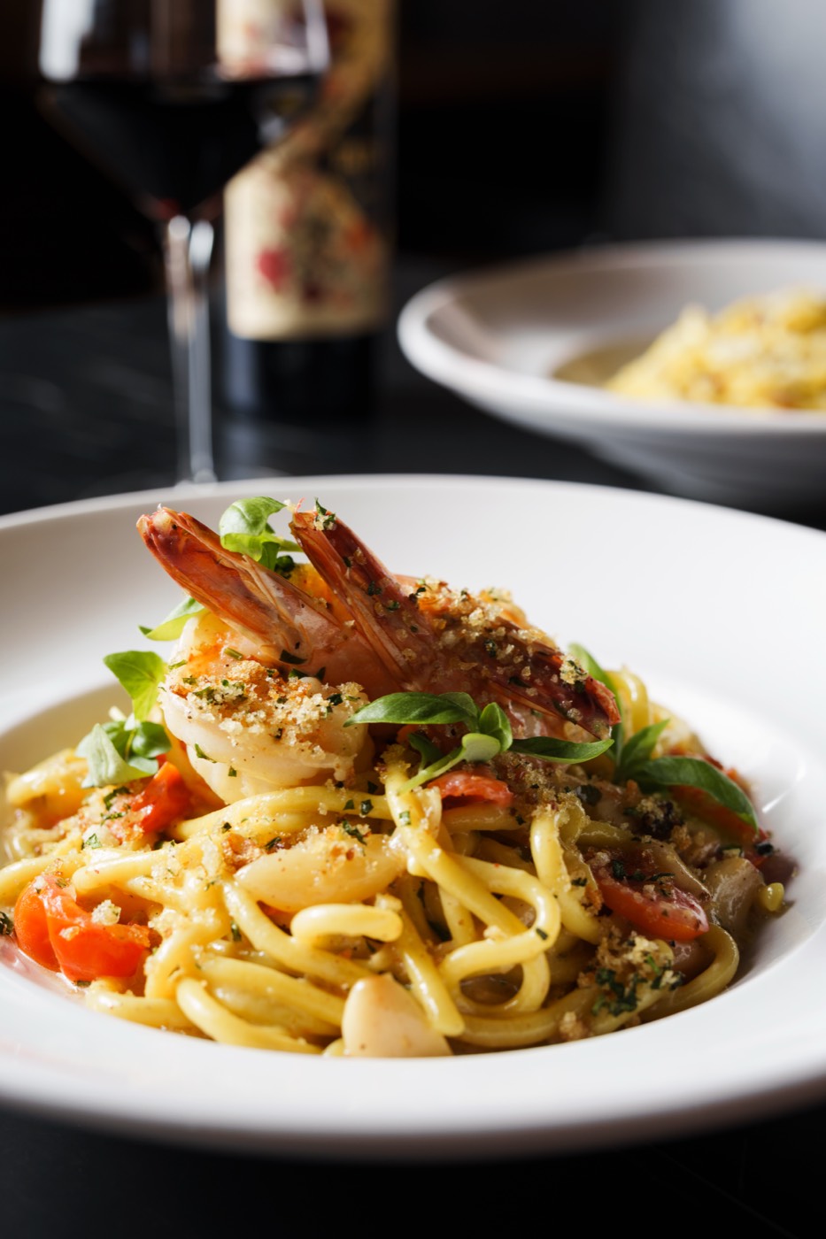 Shrimp linguine plated with a glass of red wine